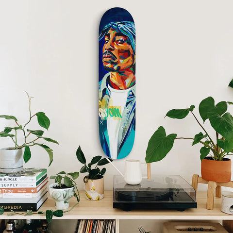 Colorful, abstract portrait painted on a skateboard deck mounted vertically on a wall.