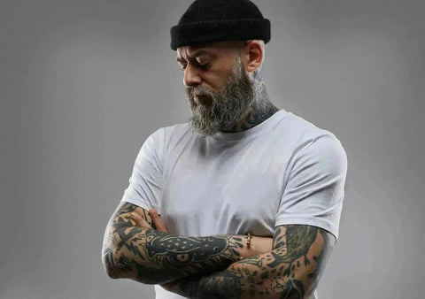 Bearded man with tattoos in white t-shirt and black cap from Hukone collection