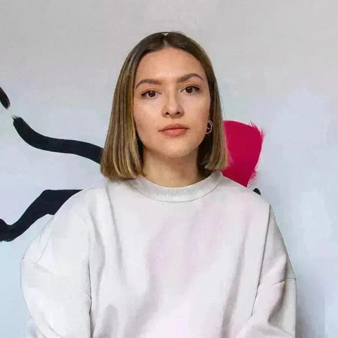 Young woman with shoulder-length blonde hair in a white sweatshirt from Mariah Birsak.