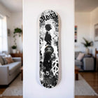 A black and white chanel skateboard deck featuring a stylized silhouette, graffiti-style graphics, and the iconic cc logo.