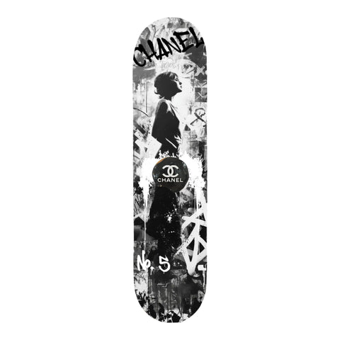 Black and white graffiti-style skateboard deck featuring a stylized silhouette of a woman, the chanel logo prominently displayed in the center, and ’no.