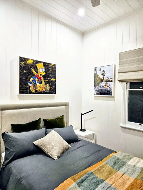 Bed with gray bedding and colorful throw blanket, flanked by pop art wall decor.