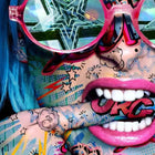 A woman with blue hair and sunglasses on her face