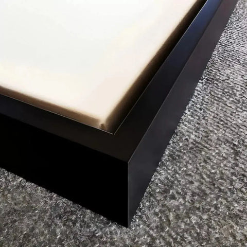 A bed with a white mattress and black frame