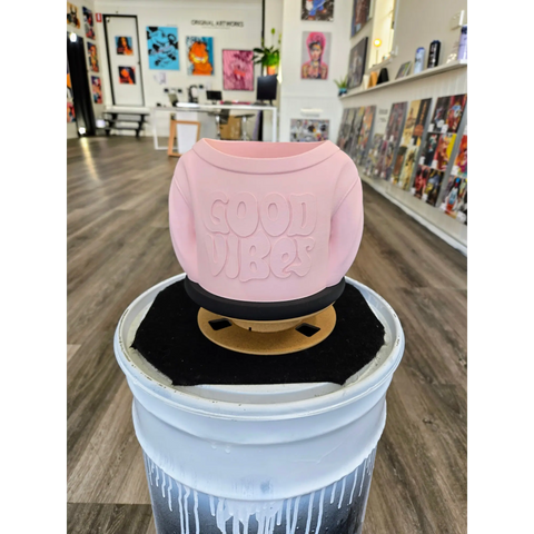Pink ceramic wax warmer with ’COOL VIBES’ embossed on its surface.
