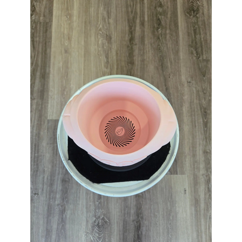 Pink and white ceramic bowl with a black spiral pattern at the bottom.
