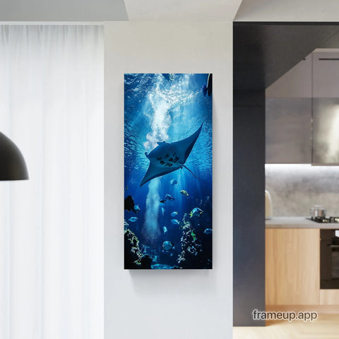 Vertical canvas print featuring a deep blue underwater scene with a prominent manta ray and schools of fish, framed in minimalist black.