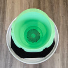 Green plastic bucket with a spiral pattern on the bottom, sitting inside a white container.