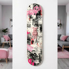 A pink bearbrick figure with ’prada’ branding sits centrally on a skateboard deck adorned with graffiti-style graphics, black and white street art elements, bold pink lettering including the word “prada,” and splashes of vibrant magenta.