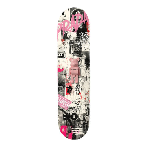 A pink bearbrick figure with ’prada’ printed on its chest sits centrally on a skateboard deck covered in black, white, and vibrant pink graffiti-style graphics.