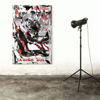 Abstract painting with black, white, and red splatters and text, displayed next to a standing spotlight.