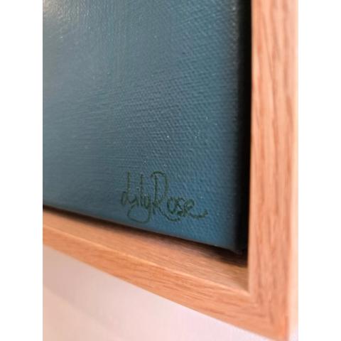 Signature or autograph on a dark blue surface, likely a painting or artwork.