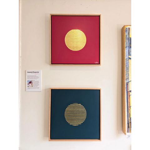 Two framed abstract artworks featuring golden circular shapes on red and blue backgrounds.