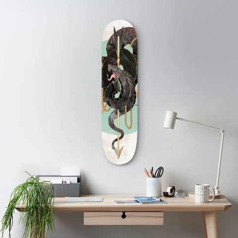Skateboard deck mounted on a wall featuring a black dragon design against a mint green and white background.
