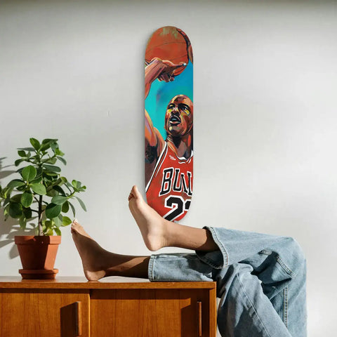 A vertically mounted skateboard deck featuring a vibrant, stylized illustration of michael jordan in his iconic red chicago bulls jersey with the number 23.