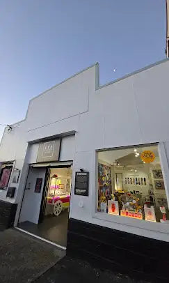 White storefront with black base and a brightly lit window display showcasing various items.